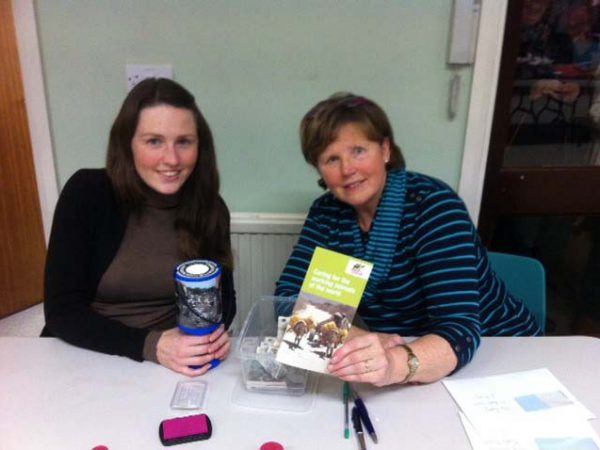 Two women sat at table with SPANA fundraising materials
