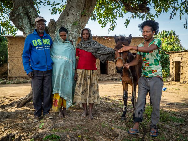 A family stands with their mule outside of their home in Ethiopia.