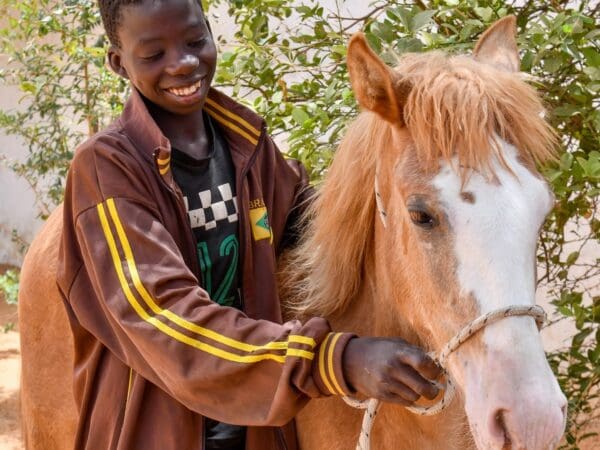 A happy young boy posts with his working horse in Africa.