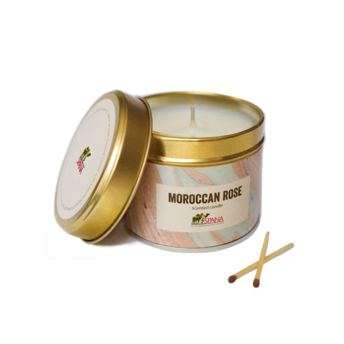 A candle in a gold tin with a pale pink label