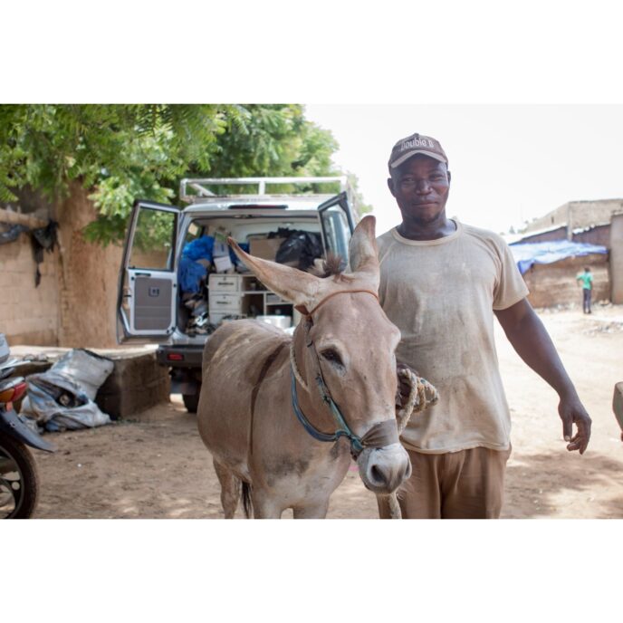 Owner and grey donkey standing outside of mobile clinic