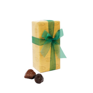 Image of a chocolate box, gift-wrapped in gold paper with a green organza ribbon and loose chocolates