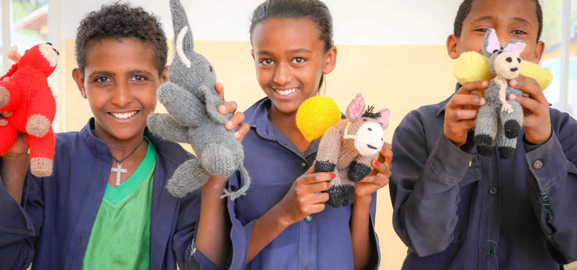 Children holding knitted animals