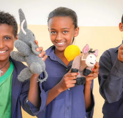 Children holding knitted animals