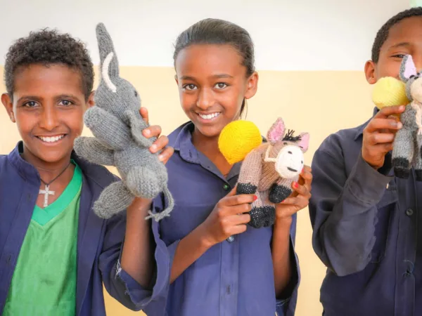 Children holding knitted animals