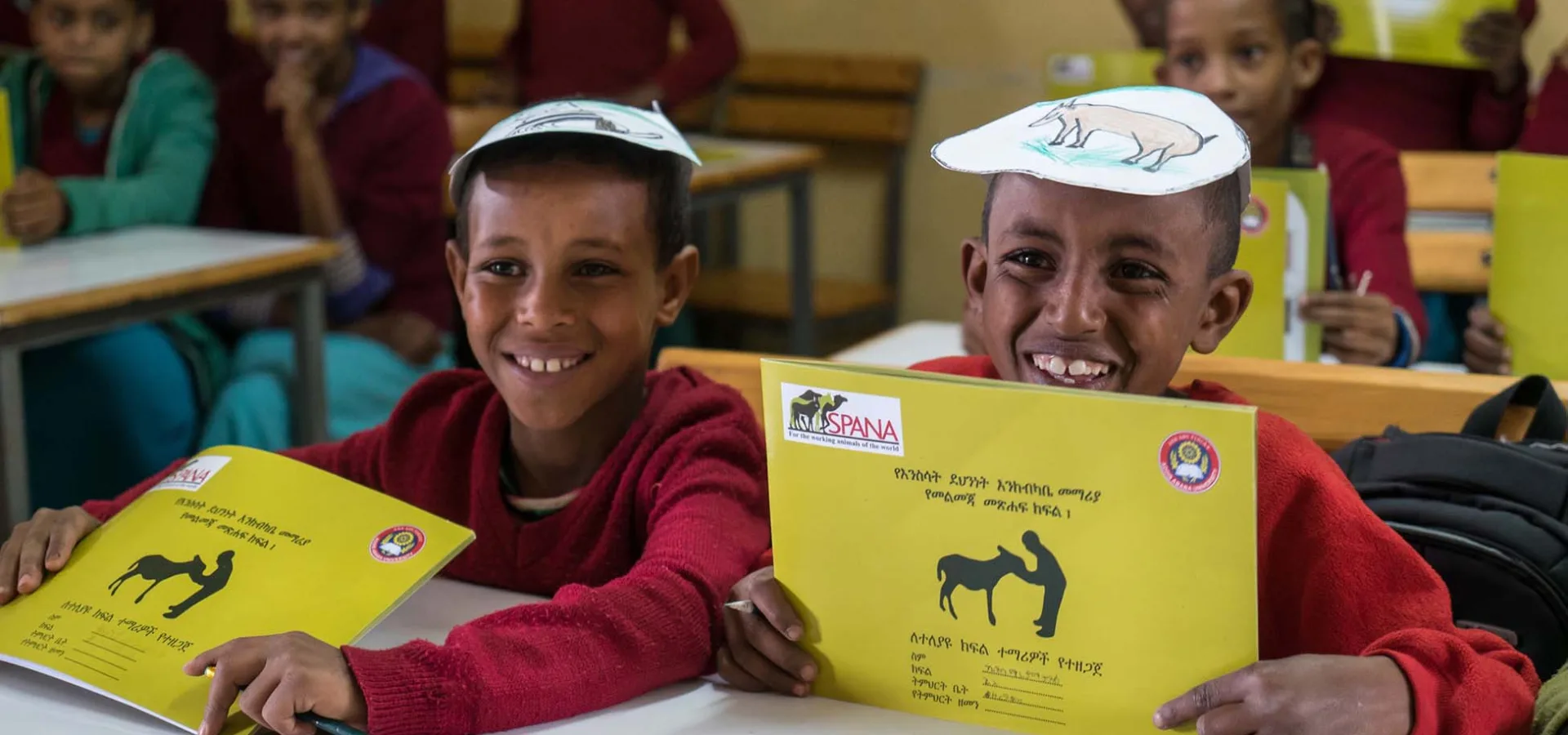 Two boys smiling with SPANA workbooks