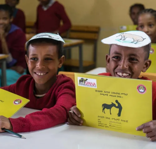 Two boys smiling with SPANA workbooks