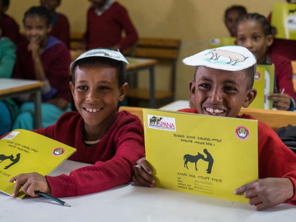 Two boys smiling with SPANA workbooks