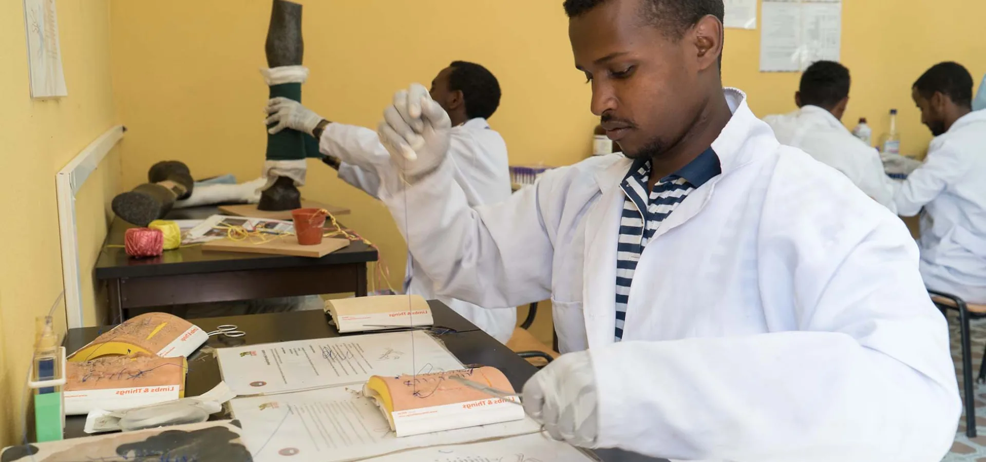 Man in white lab coat practising stitching