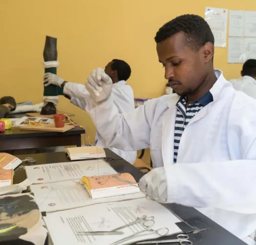 Man in white lab coat practising stitching