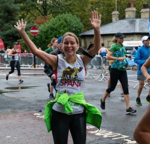 Woman celebrating SPANA run with arms raised at Royal Parks Half Marathon