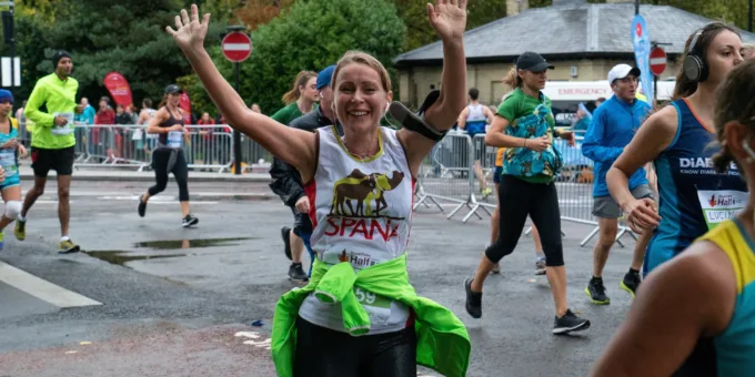 Woman celebrating SPANA run with arms raised at Royal Parks Half Marathon