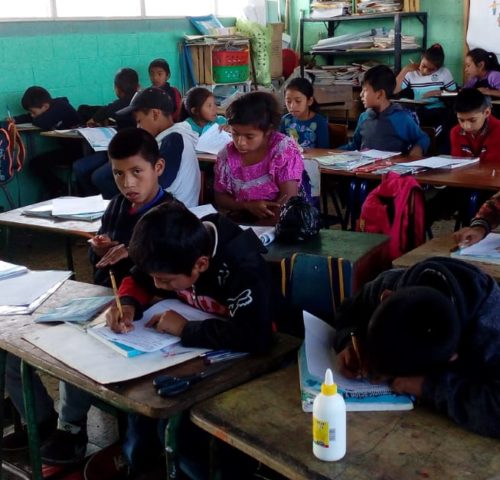 School children in Guatemala sitting at desks writing in notebooks