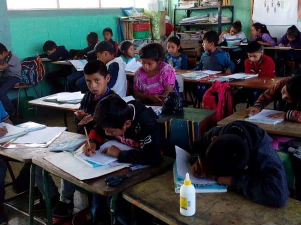 School children in Guatemala sitting at desks writing in notebooks