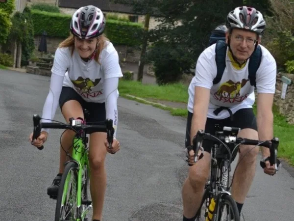 A man and woman searing SPANA shirts cycle to raise money for working animals.