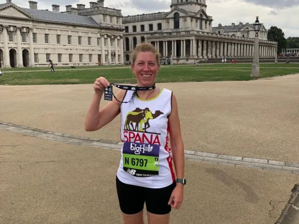 A lady wearing a SPANA shirt smiles as she poses with her medal.