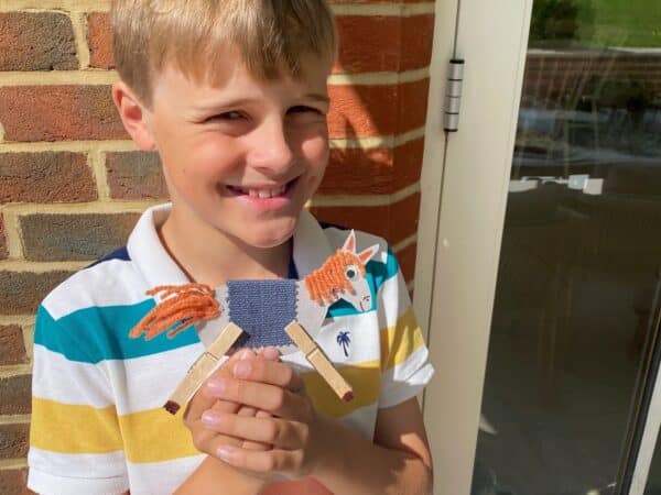 A young boy holding a colourful paper horse he crafted for charity.